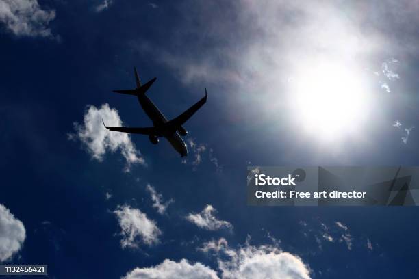 A Jet Airliner Flying Under The Sun Shining In The Sky Stock Photo - Download Image Now