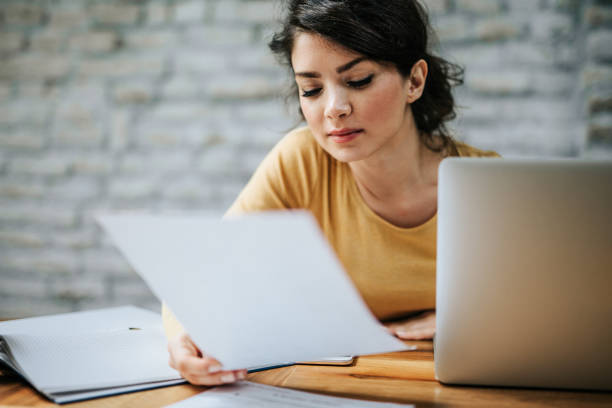 istock Young beautiful woman going through paperwork while working at home. 1132457781