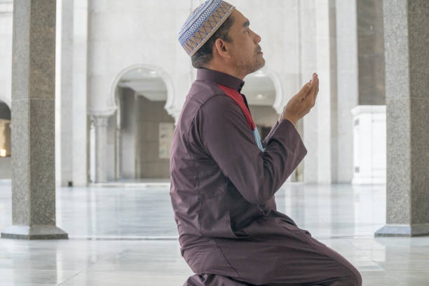 istock Side View Of Mature Man Praying While Kneeling At Mosque 1132457908
