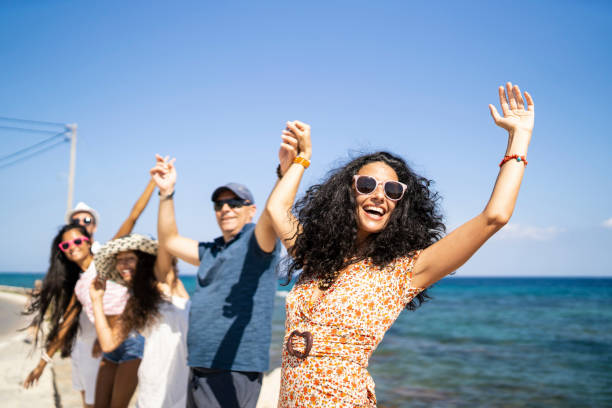 istock Group of tourists standing arms raised on beach 1132465759