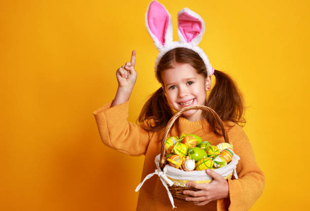istock funny happy child girl with easter eggs  on yellow 1132468095