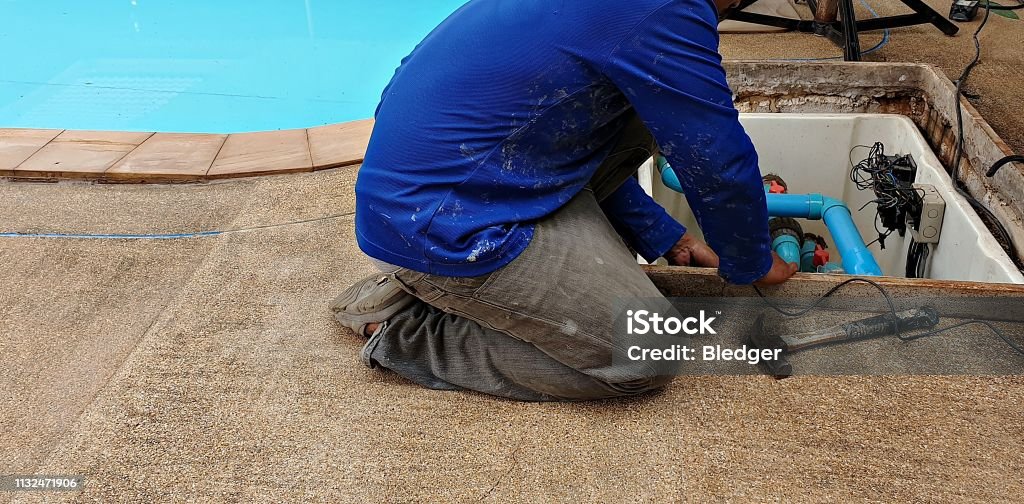 Swimming pool maintenance Technician fixing swimming pool water pump. Service and maintenance for swimming pool. Swimming Pool Stock Photo