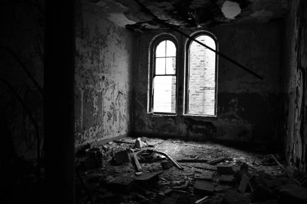 istock Empty school room in monochrome with arched window during day time illuminating peeling walls and debris. 1132471943