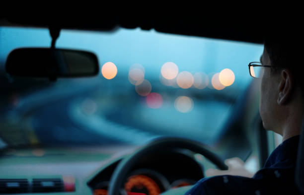 Hands of a driver on steering wheel of a car with empty asphalt road background. High-quality free stock image of driver hands on the steering wheel inside
