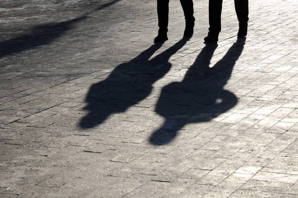 menschen, die die straße hinunterlaufen, schwarze silhouetten und schatten auf dem fußgängersteig - sidewalk walking human foot city stock-fotos und bilder