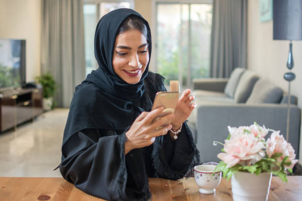 집에서 휴대 전화를 사용 하 여 웃는 아라비아 여자의 초상화 - 아랍문화 뉴스 사진 이미지