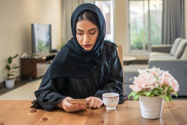 istock Young muslim woman wearing hijab using phone at home 1132475621