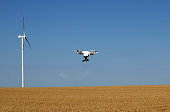 drone flying over wheat field with wind turbine