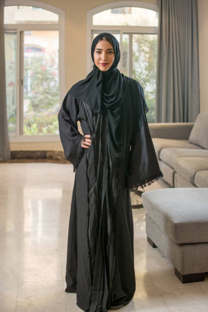 полный портрет мусульманской молодой женщины в хиджабе, стоящей дома - arab woman стоковые фото и изображения