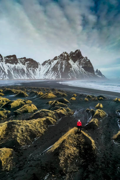Exploring Stokksnes bay Mature woman standing in a sand dune looking at Stokksnes bay with Vestrahorn mountain in the background. iceland stock pictures, royalty-free photos & images