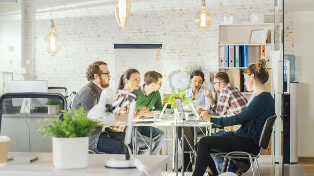 Seven Stylish People Having Planning Business Session Sitting at Big Table in their Bright Modern Creative Office. Seven Stylish People Having Planning Business Session Sitting at Big Table in their Bright Modern Creative Office. real estate office photos stock pictures, royalty-free photos & images