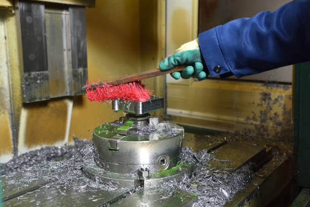 istock Worker removes metal shavings with a brush after working on a CNC machine 1132480576