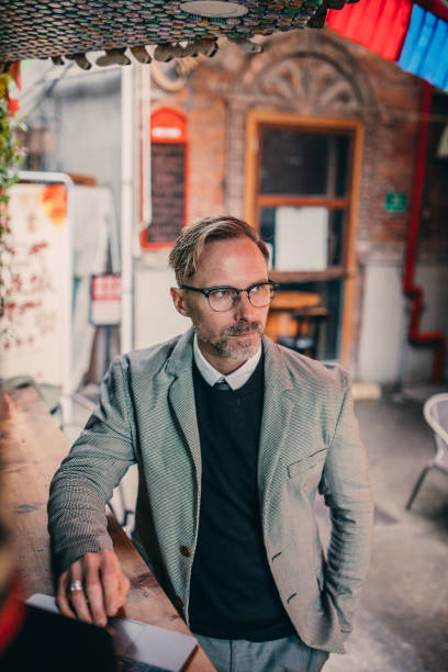 istock Handsome mature businessman using laptop in sidewalk cafe 1132483963