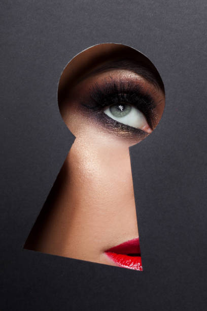 young luxurious woman looks at something secret in the keyhole. The concept of secret of beauty, new cosmetics. young luxurious woman looks at something secret in the keyhole. The concept of secret of beauty, new cosmetics. Eye makeup close - up, woman spying through a keyhole stock pictures, royalty-free photos & images