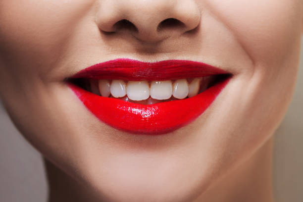 istock Beautiful women's lips with bright red lipstick and white teeth. 1132485666