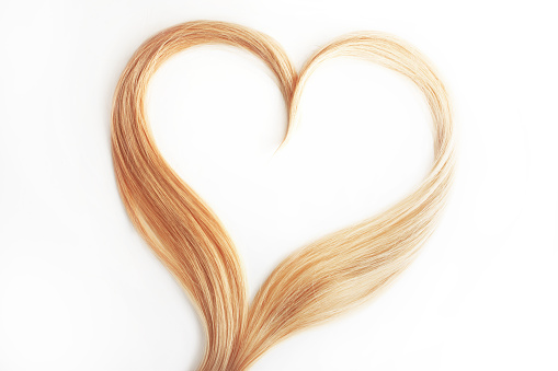strand of blond hair isolated on white. Curls of hair in the shape of a heart, health and hair care concept