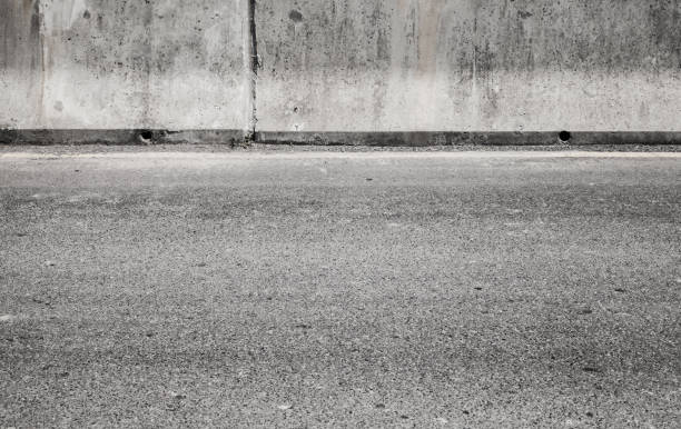 istock Grungy gray concrete wall and asphalt road 1132489929