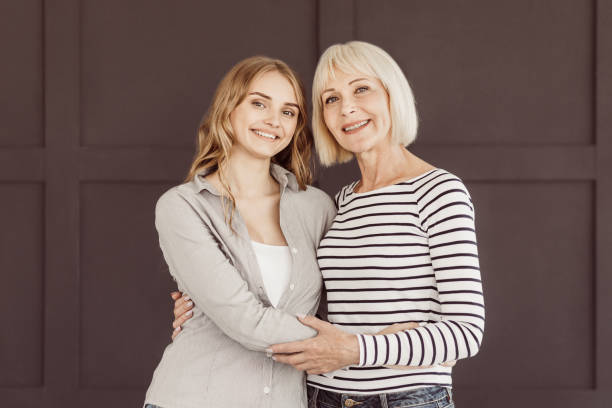 istock Happy mom and daughter looking at camera over brown wall 1132490602