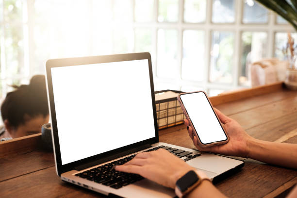 istock Mockup image of a businesswoman using laptop with blank white desktop screen with coffee cup on wooden table in cafe 1132491021