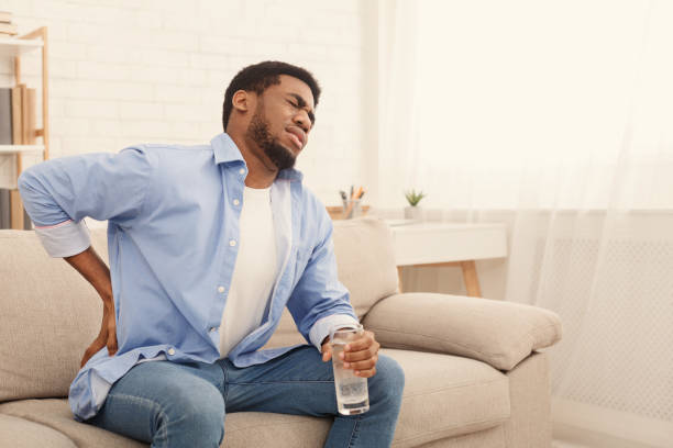 Young black man with back pain at home