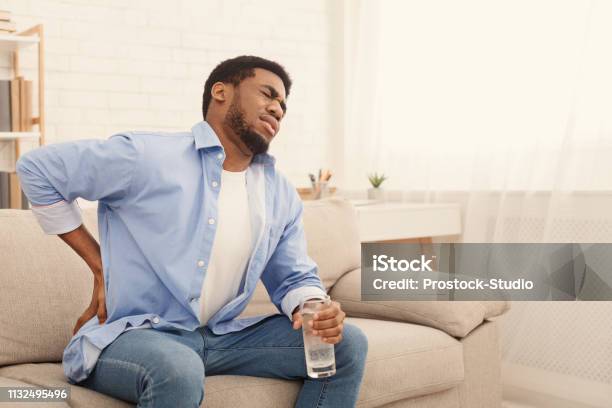 Young Black Man With Back Pain At Home Stock Photo - Download Image Now - Pain, Muscular Build, Backache