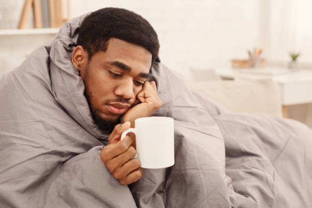 istock Cold black man with flu wrapped in warm blanket 1132495500