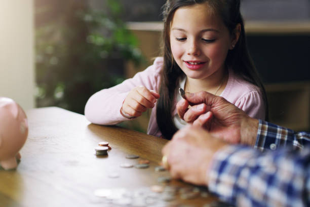 The earlier the better Shot of a little girl learning about money from her grandfather counting coins stock pictures, royalty-free photos & images