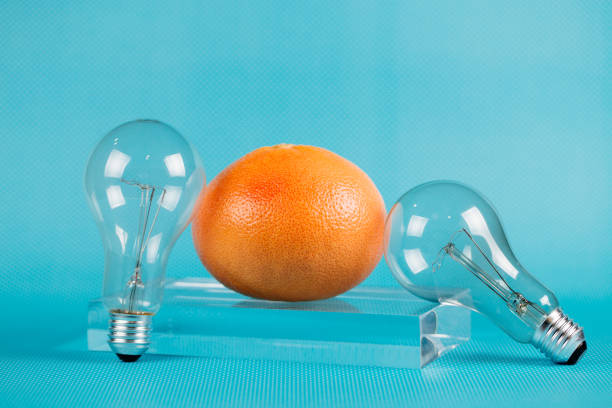 istock Different kinds of fruit and electric bulbs on blue background. 1132498934