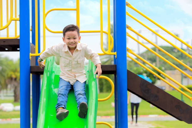istock Portrait Of Cute Boy Sliding On Slide In Park 1132500453