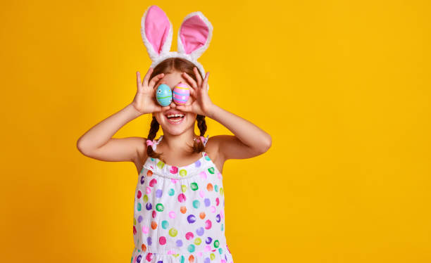 istock funny happy child girl with easter eggs  on yellow 1132505291