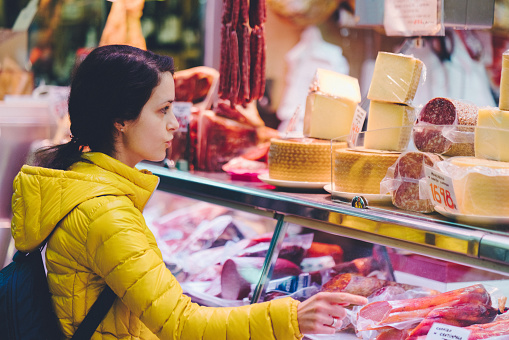 Tourist woman at the butcher’s shop choosing delicatessen food