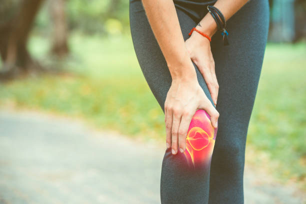 woman holding her knee with red pain - rheumatism imagens e fotografias de stock