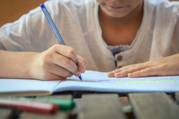 istock Midsection Of Boy Writing In Book On Table 1132510384