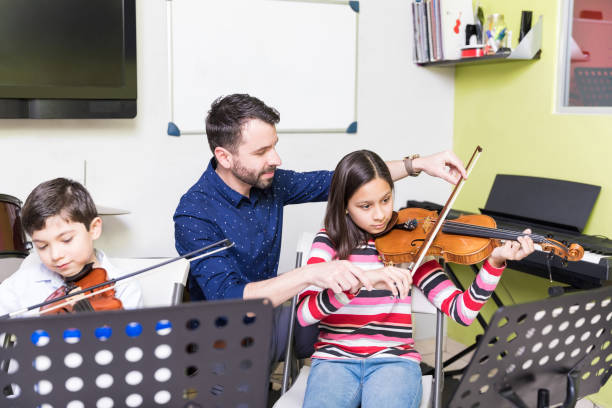 niedliche kinder lernen, in der klasse violine zu spielen - music lessons stock-fotos und bilder