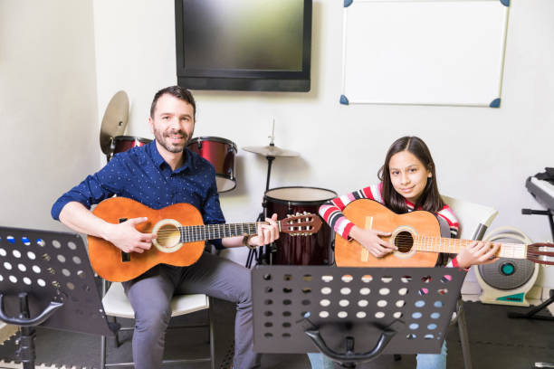 istock Hispanic Girl Taking Guitar Lessons From Tutor 1132515963