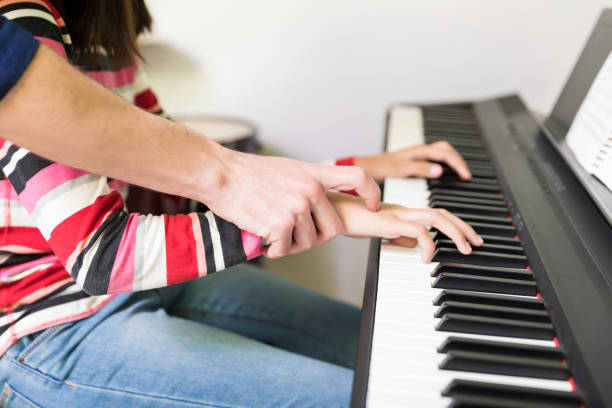 istock Midsection Of Girl Taking Piano Lessons From Tutor 1132516269