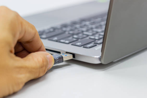 istock Hand of a businessman holding a USB device connected to Laptop computer 1132516856