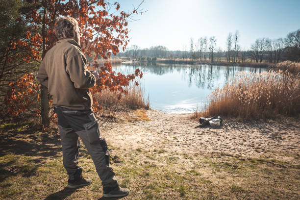 istock Man with a coffee mug overlooking a small lake 1132517597