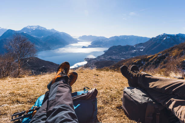 Couple of hikers resting on a hill, lake in background Hiking over lake lake como photos stock pictures, royalty-free photos & images