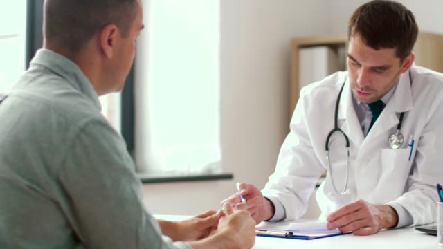 doctor writing prescription for patient at clinic