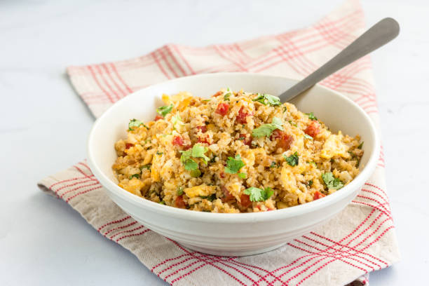 Stir-Fried Cauliflower Rice in a Bowl Stir-Fried Cauliflower Rice with Veggies in a Bowl on White Background. Healthy Weight Loss Food - Popular Cauliflower Dish. fried rice stock pictures, royalty-free photos & images