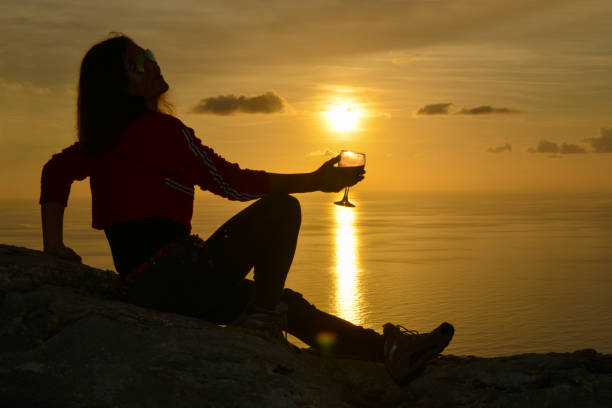 istock Woman raising toast to the setting sun. 1132523663