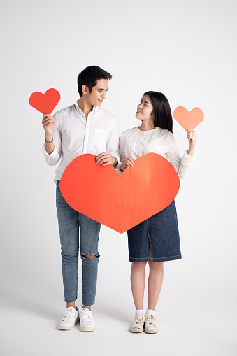 Young happy couple in love holding red paper heart