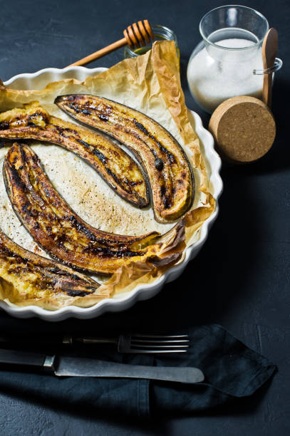 istock Baked bananas with honey in a baking dish. Black background, top view, space for text. 1132524314