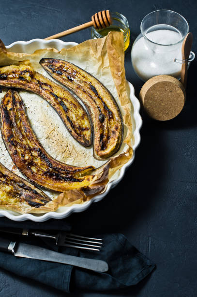 istock Fried bananas with honey in a baking dish. Black background, top view, space for text. 1132525552
