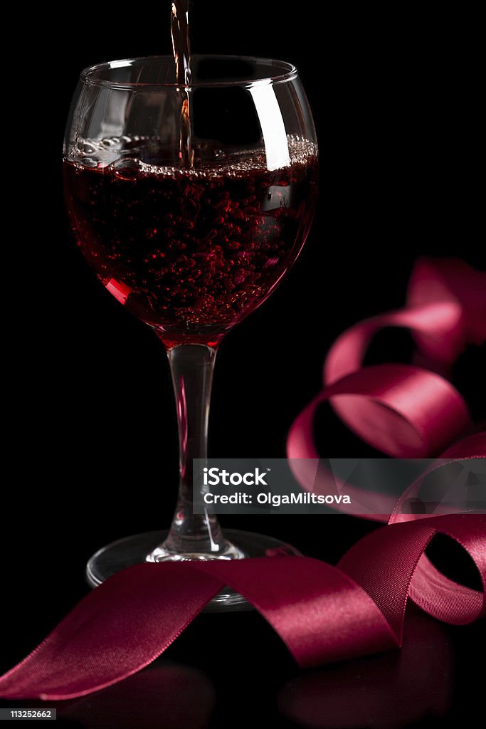 red wine pouring into glass isolated over black background  Alcohol - Drink Stock Photo