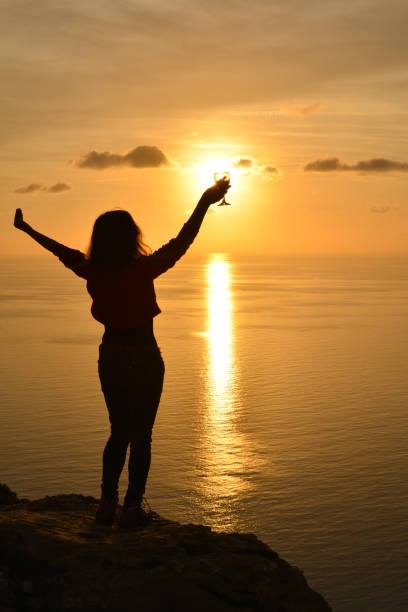 istock Woman raising toast to the setting sun. 1132528294