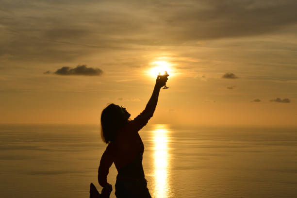 istock Woman raising toast to the setting sun. 1132528759