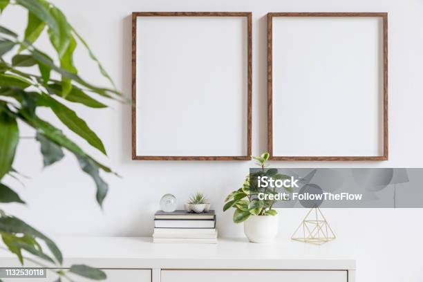 Stylish Home Interior With Two Brown Wooden Mock Up Photo Frames On The White Shelf With Books Beautiful Plants Gold Pyramid And Home Accessories Minimalistic Concept Of White Room Decor Stock Photo - Download Image Now