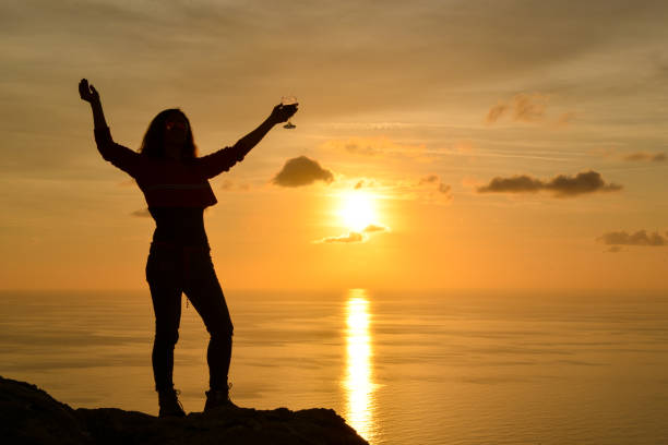 istock Woman raising toast to the setting sun. 1132533570